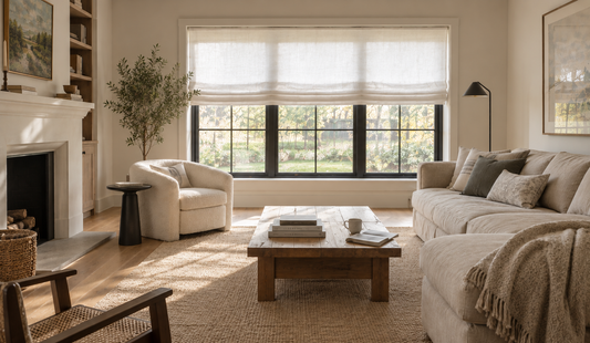 Modern rustic living room with a white relaxed roman shade, painted fireplace and bouclé armchair